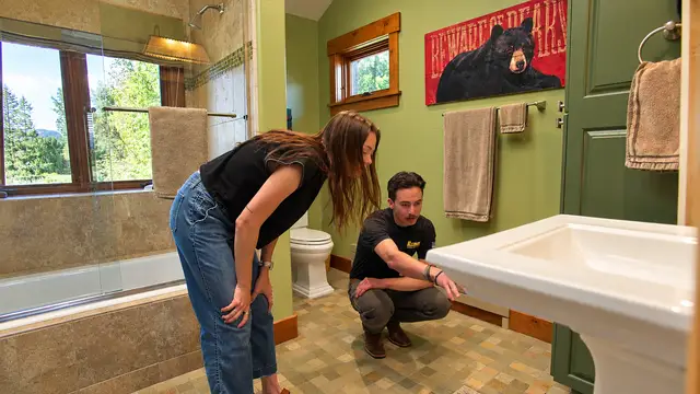Plumber walking a homeowner through a bathroom plumbing inspection