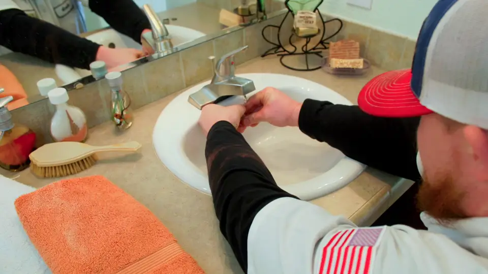 Element plumber repairing a bathroom sink faucet