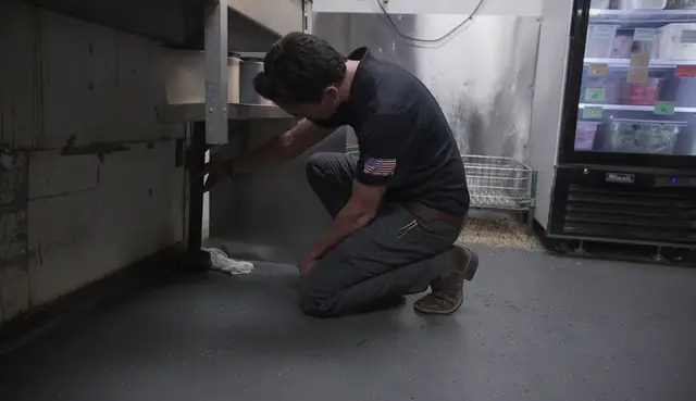 Plumber checking a floor drain in a commercial kitchen