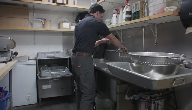 Plumber working at a commercial kitchen's prep sink