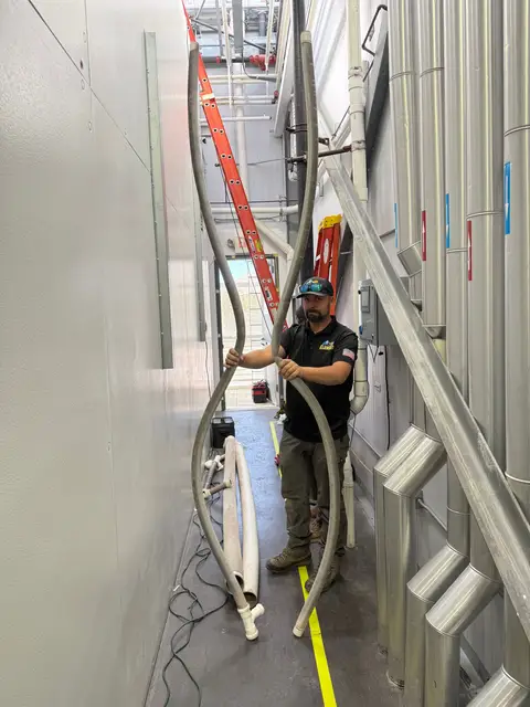 Element plumber running flexible lines through a commercial utility corridor