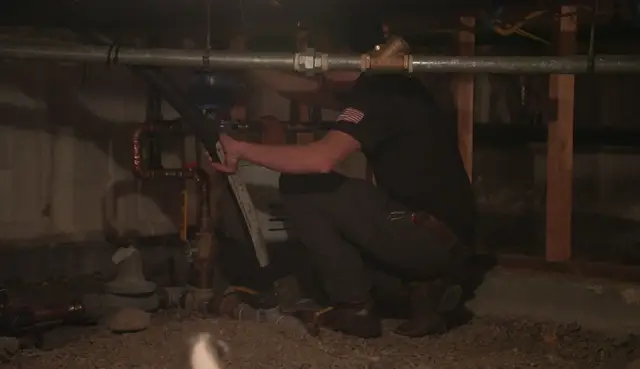 Plumber repairing water lines in a crawl space