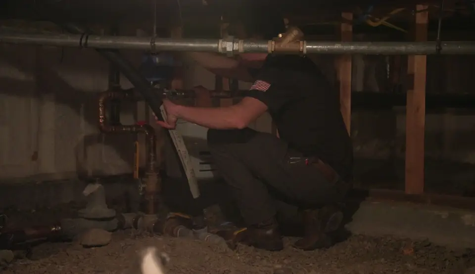 Plumber repairing water lines in a crawl space