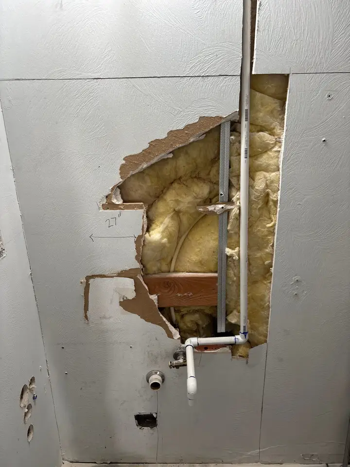 Drywall opened to reach a leaking pipe behind the wall