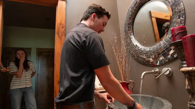 Plumber checking water flow at a bathroom faucet with the homeowner