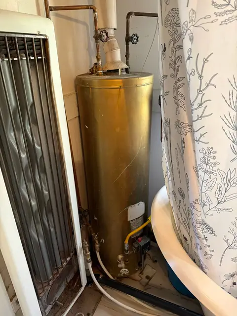 Older gas tank water heater tucked into a closet beside a wall heater