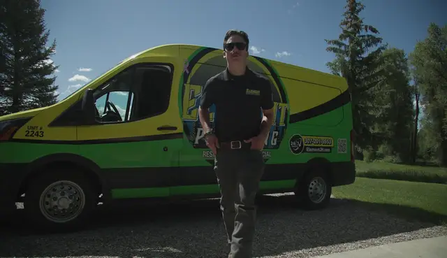 Element plumber standing in front of the service van