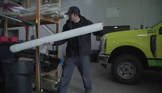 Element plumber carrying PVC pipe through the shop