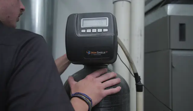 Technician's hands on a water treatment control head