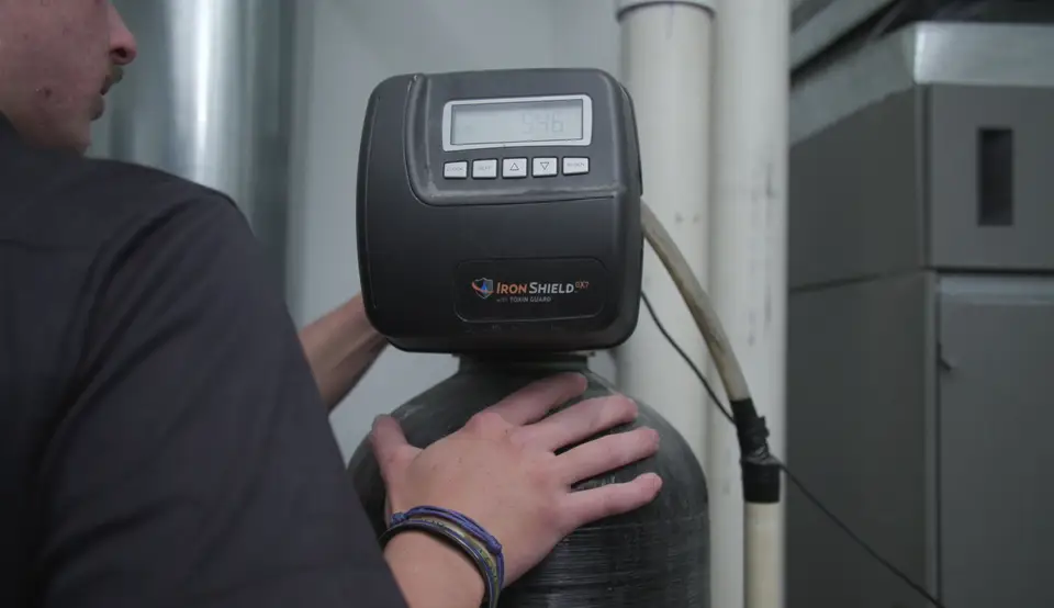 Technician's hands on a water treatment control head