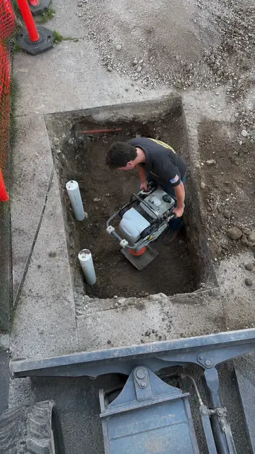 Plumber installing a new water service line in a trench