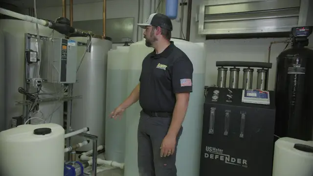 Technician walking through a water treatment room with storage tanks and filters