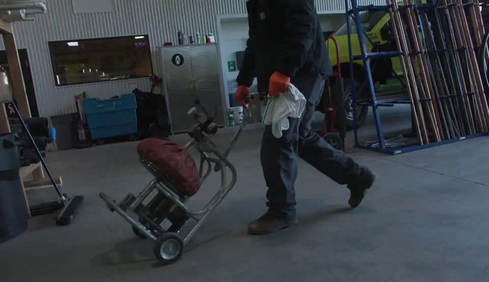 Plumber wheeling a drain cleaning machine out to the truck
